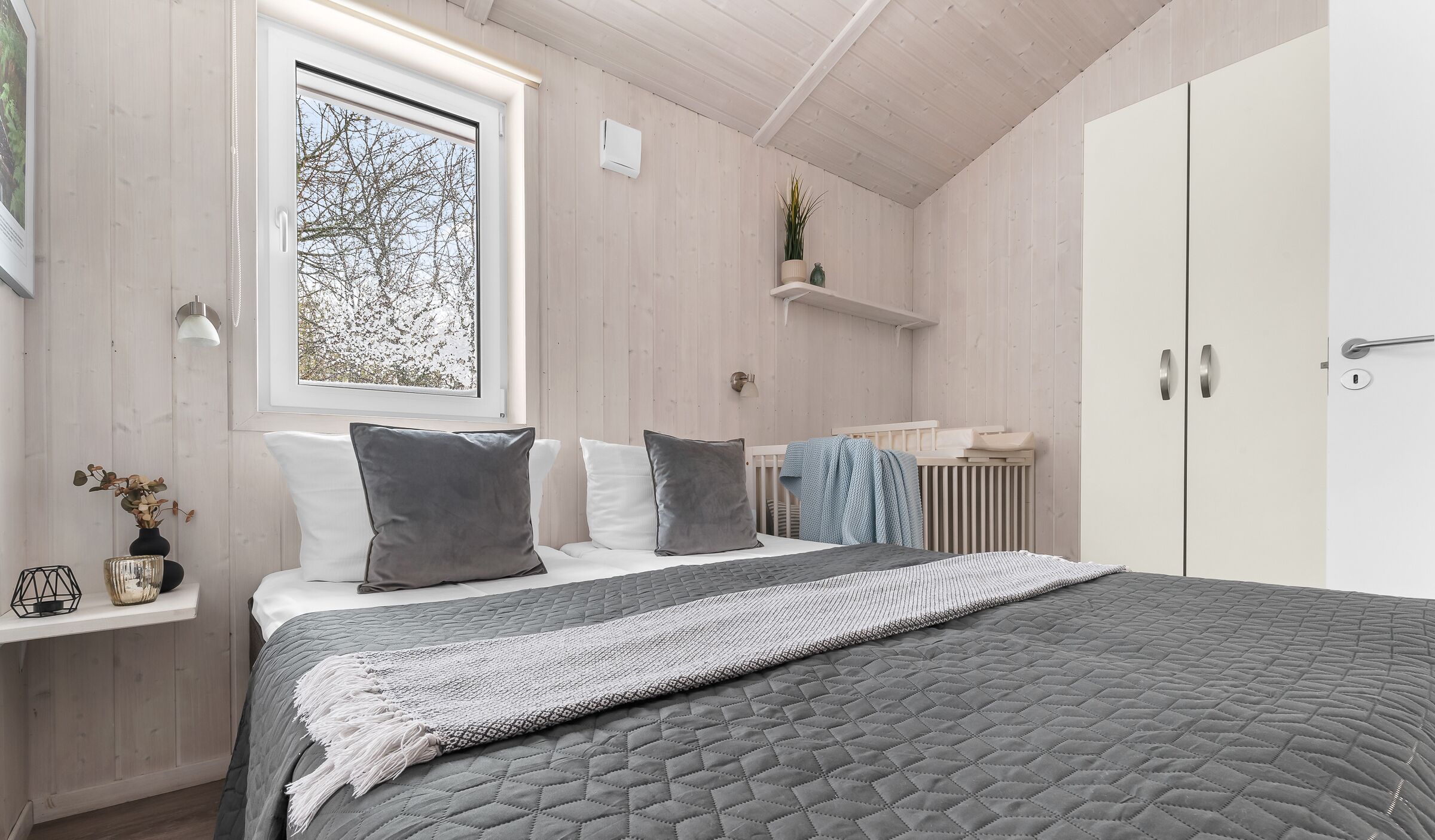 Quarto com cama, mesa de cabeceira, janela e guarda-roupa.
