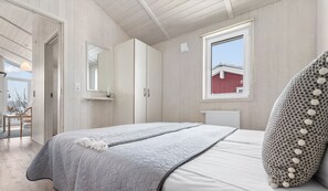 A bedroom with a bed, a window, a radiator, and a wardrobe.