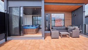Eine moderne Terrasse im Freien mit Whirlpool, Korbmöbeln und einer Holzbeschichtung.