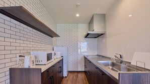 Eine moderne Küche mit weißen Ziegelsteinplatten, Holzboden und Edelstahlgeräten.