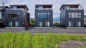 Ein modernes Wohngebäude mit Flachdach, großen Fenstern und einem Balkon.