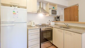 A compact kitchen with a refrigerator, stove, microwave, and a coffee maker.