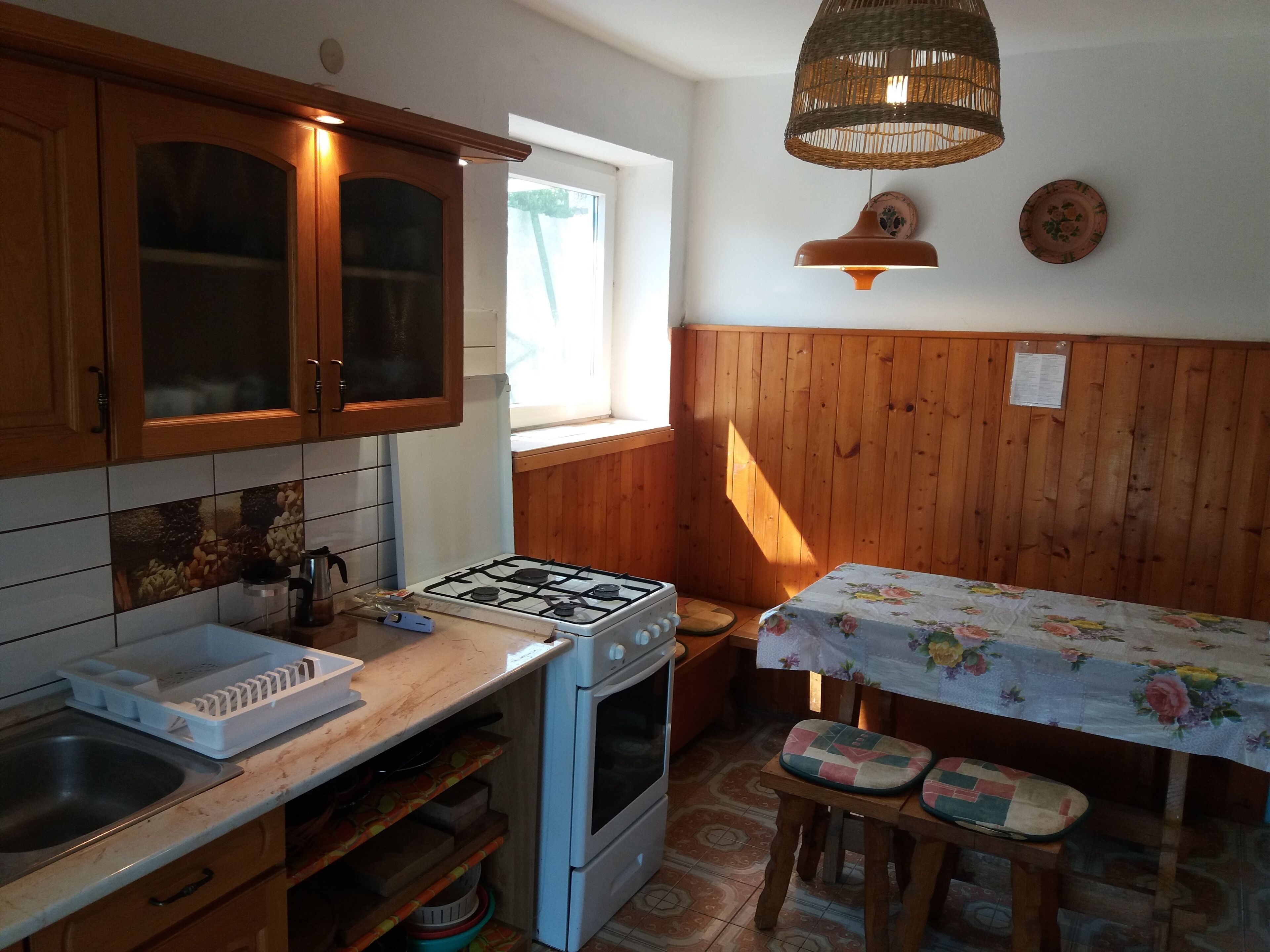 Une cuisine dotée de meubles en bois, d’une cuisinière à gaz, d’un évier et d’un coin repas avec une table et des chaises.