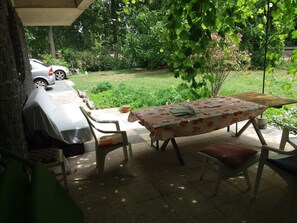 An outdoor patio with a table and chairs, a covered area, and a car parked nearby.