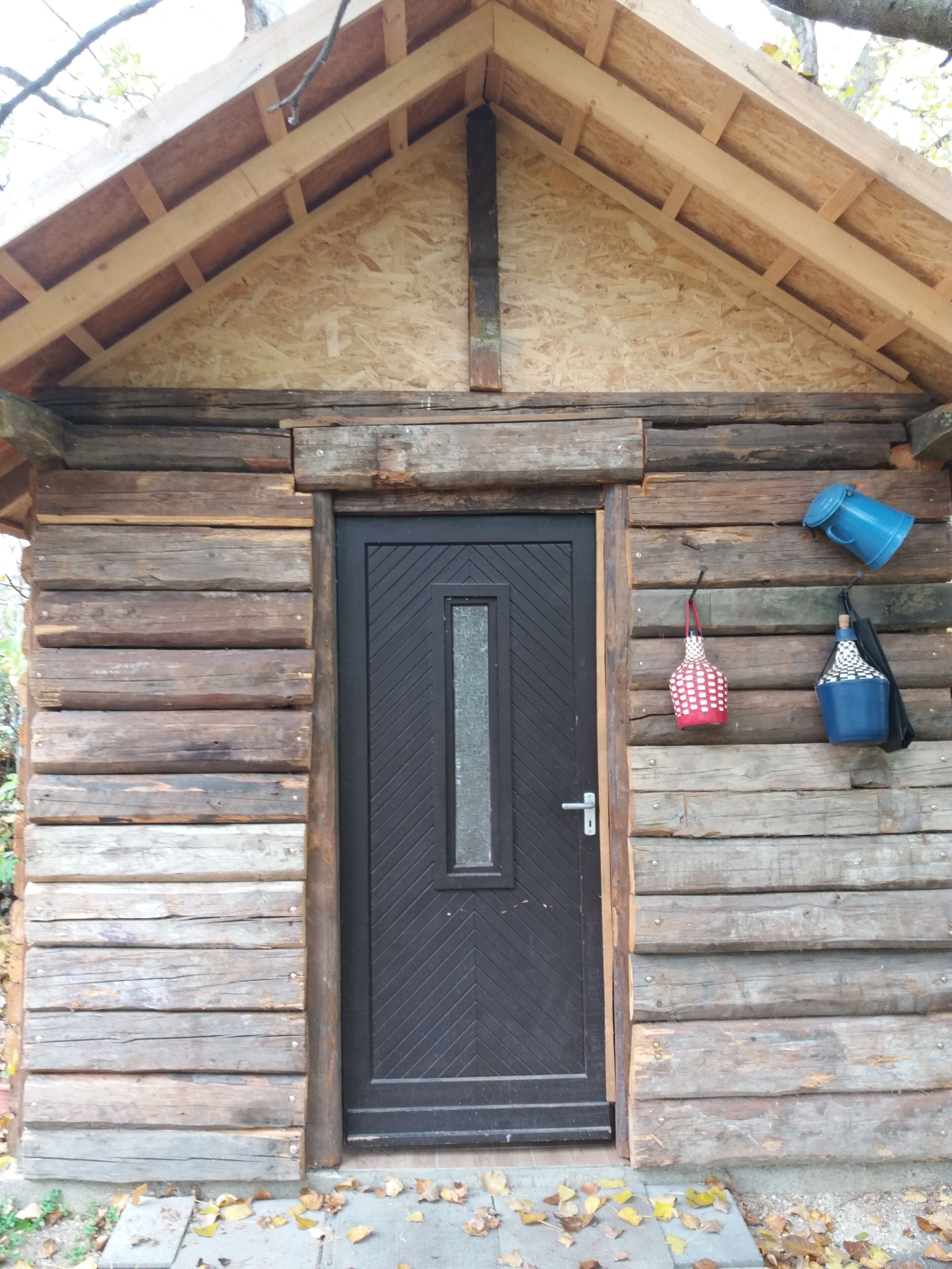 Una cabaña de troncos con una puerta de madera oscura, un pequeño porche y un picaporte de metal.