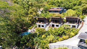 Une maison moderne à plusieurs étages, dotée d’une piscine et entourée d’une végétation luxuriante.