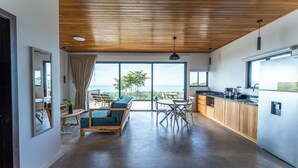 Une cuisine moderne avec un plafond en bois, de grandes fenêtres et une vue sur la mer.