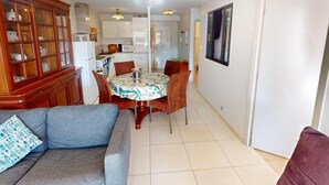 A modern kitchen with white cabinets, a dining table with chairs, and a grey sofa. - Quiet 2-room with terrace, pool, parking and wifi (Menton)