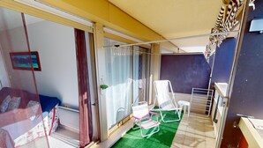 A balcony with a green mat, white chairs, and a small table. - Quiet 2-room with terrace, pool, parking and wifi (Menton)
