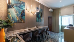 Una cocina moderna con encimera de mármol, asientos tipo bar y arte abstracto en la pared.