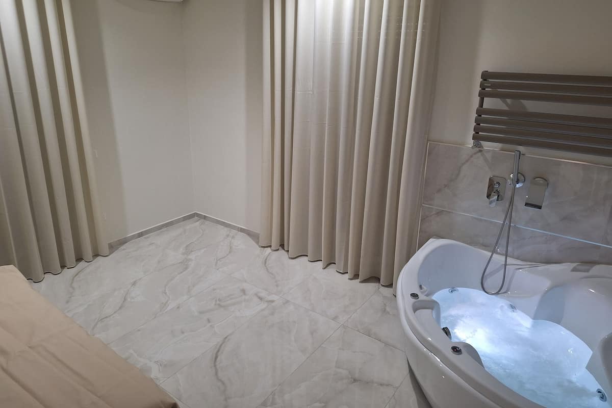 A bathroom with a marble floor, a bathtub with running water, and a towel rack.