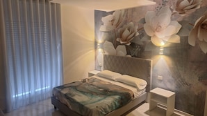 Un dormitorio moderno con cama, mesita de noche, lámpara de pared y un amplio mural floral.