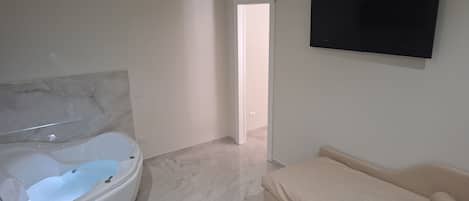 Un baño moderno con una bañera independiente y un sofá color beige en una sala de estar.