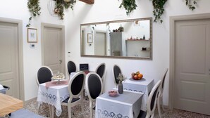 A dining area with a white table, black chairs, and a mirror above. - B&B Al Pozzo di Luce  (Venice)