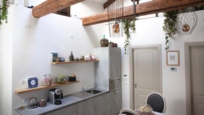 A compact kitchen with wooden beams, a built-in sink, and various kitchen items on shelves. - B&B Al Pozzo di Luce  (Venice)