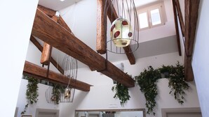 A spacious interior with exposed wooden beams, hanging light fixtures, and potted plants. - B&B Al Pozzo di Luce  (Venice)