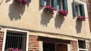 A building with multiple windows, some with shutters, and flower boxes on the windowsills. - B&B Al Pozzo di Luce  (Venice)