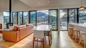 Eine moderne Küche mit großem Esstisch, Barhocker und einer Couch.