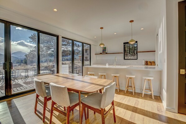 A modern kitchen with a large island, bar stools, and a view of the outdoors.