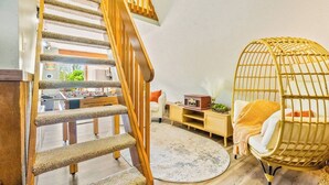 A cozy living area with a wooden staircase, a wicker chair, and a round rug.