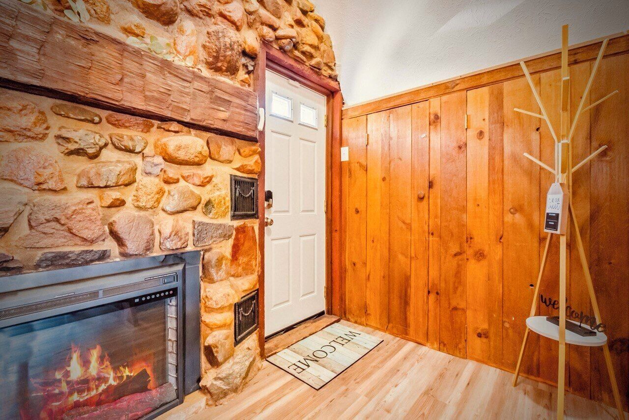 A stone fireplace with a modern TV, a wooden door, and a wooden wall.