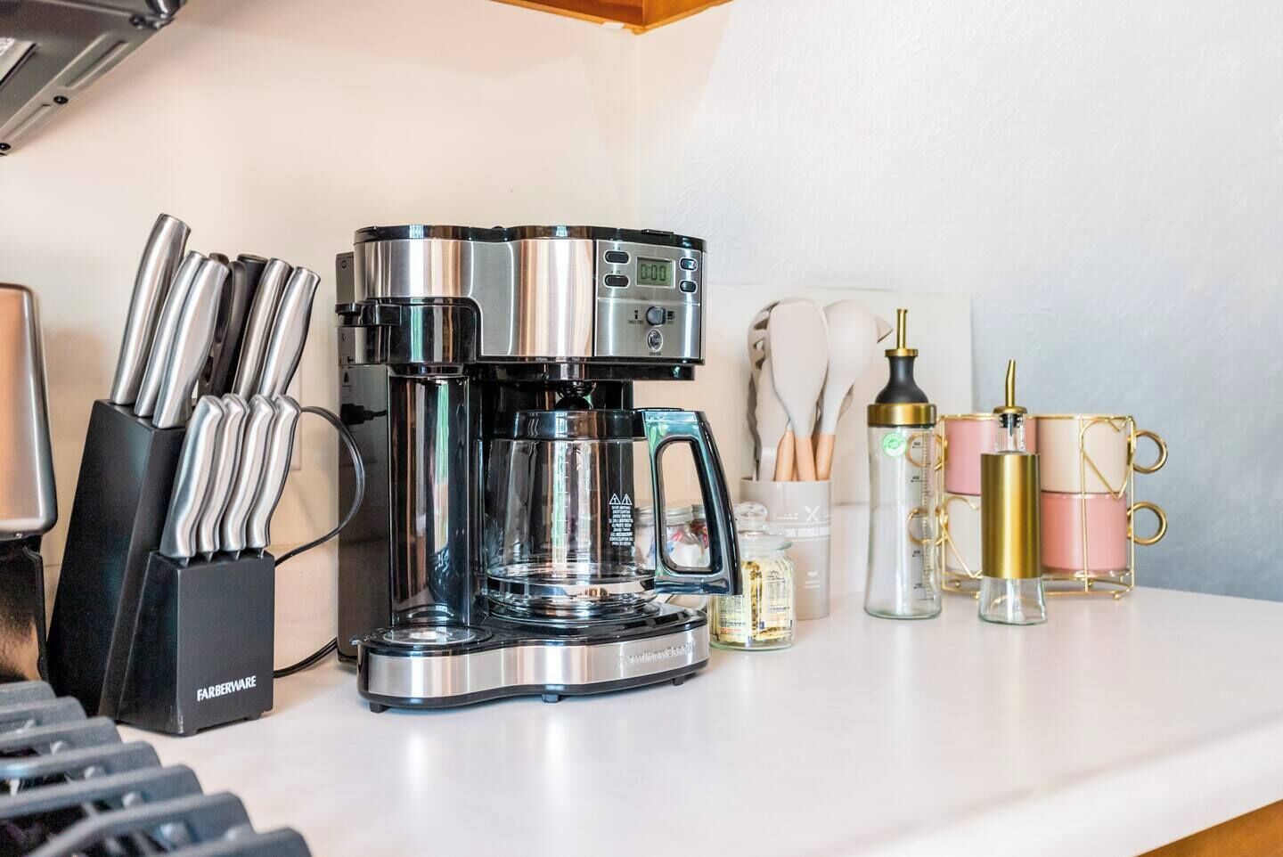 Una cocina con cafetera, juego de cuchillos y diversos utensilios de cocina.