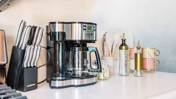 Una cocina con cafetera, juego de cuchillos y diversos utensilios de cocina.