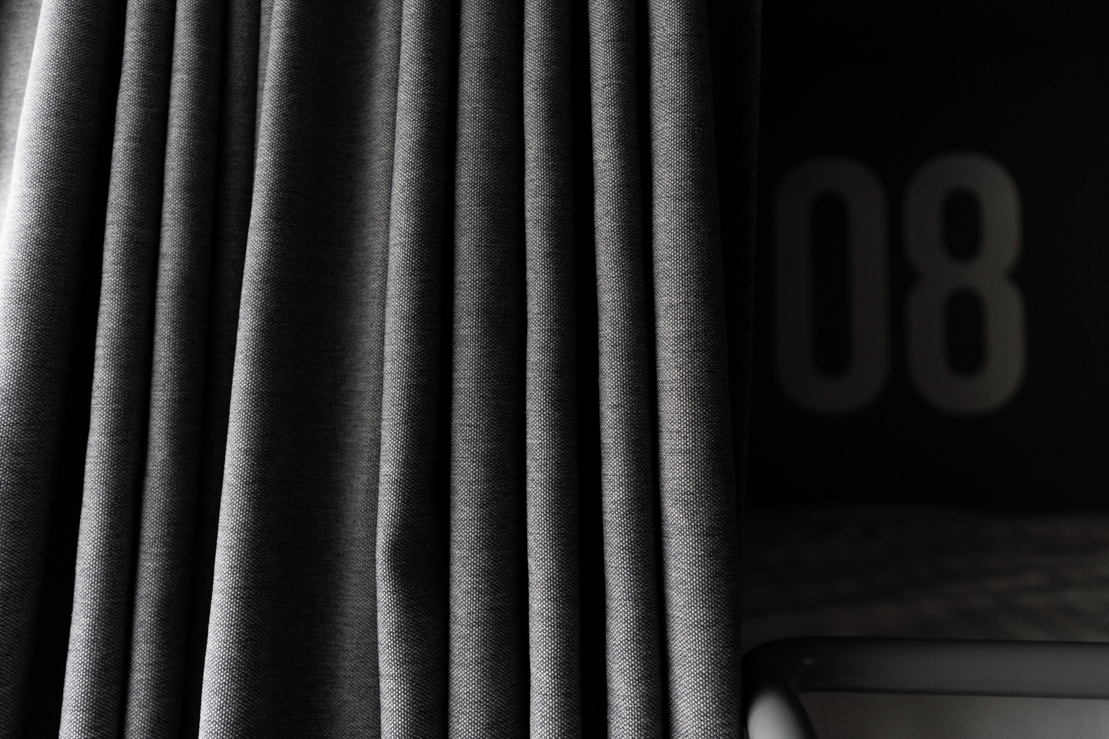 A close-up of a curtain with a partial view of a room number '08' on the wall.