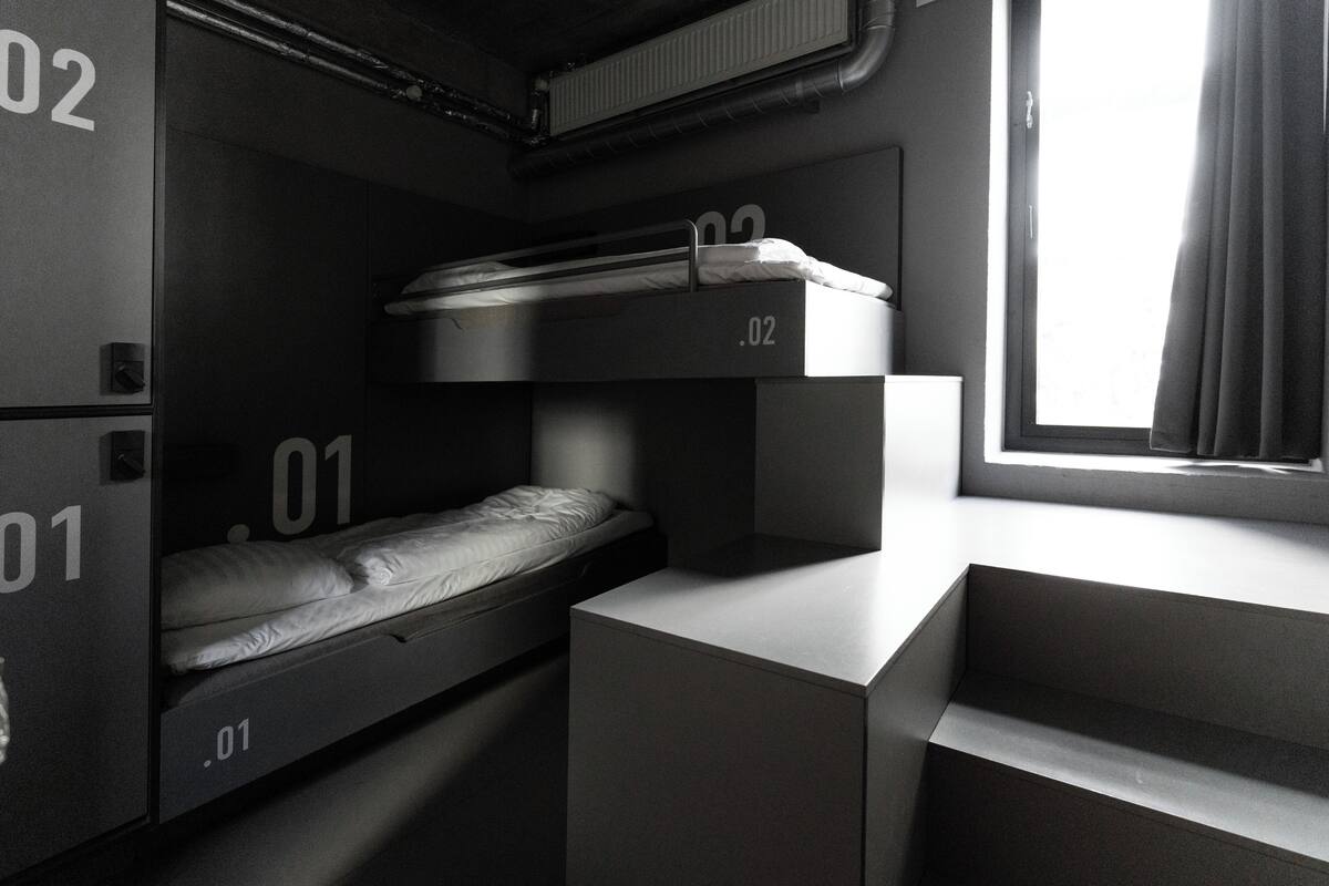 A bunk bed room with three levels, each marked with a number. There is a window with curtains, and the room has a modern, minimalist design.