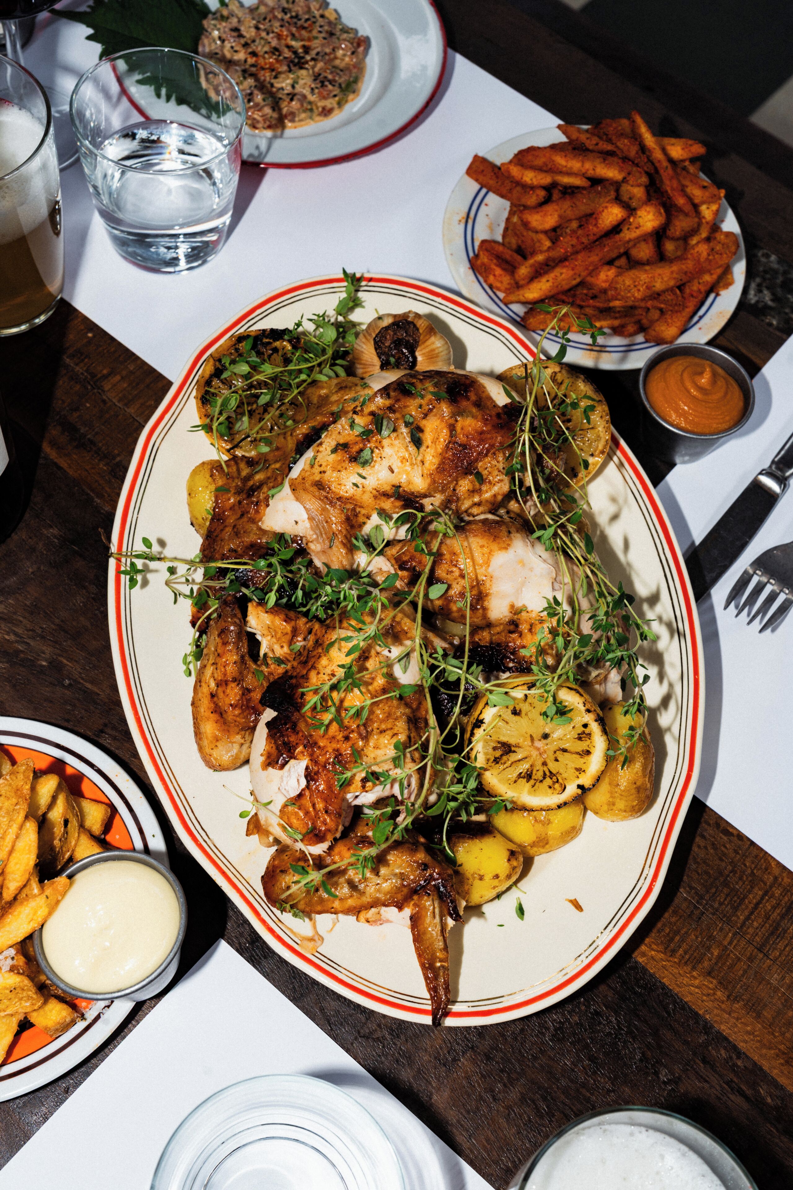 A dining table with various dishes including grilled chicken, fries, and a salad.