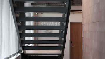 A modern staircase with metal railings and a wooden door at the bottom.