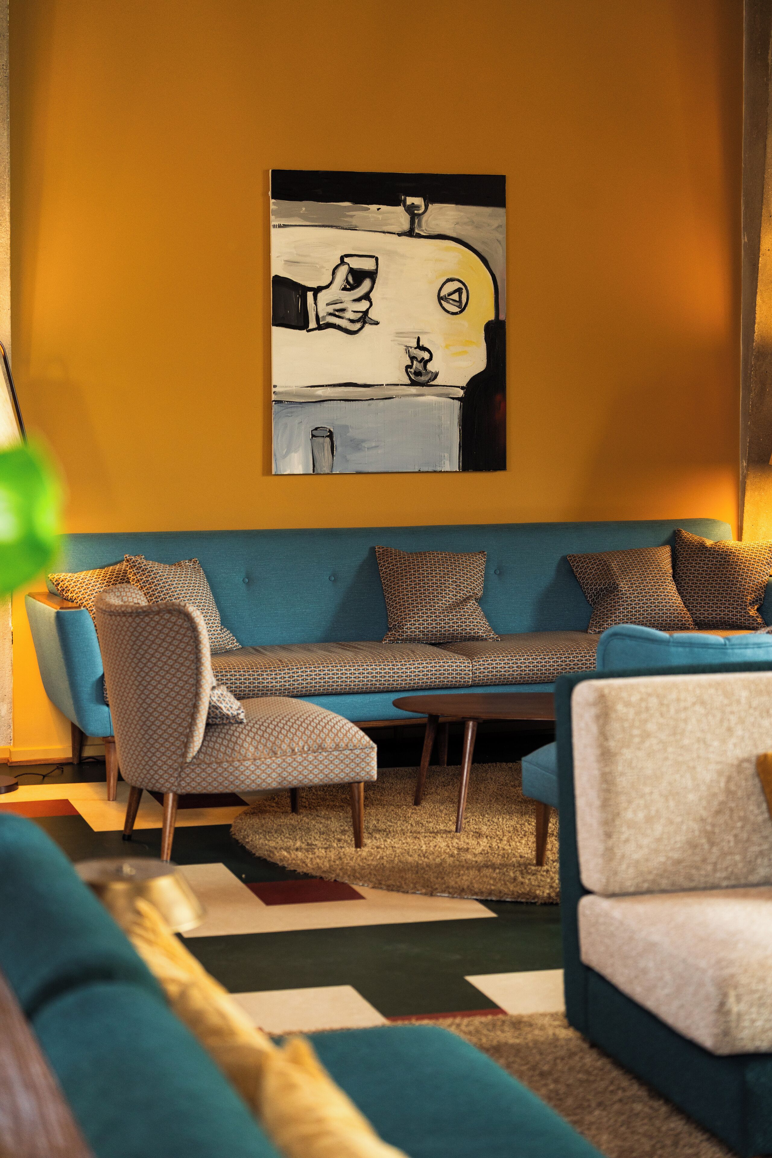 Una sala de estar con un sofá azul, sillones estampados y una mesa de centro.