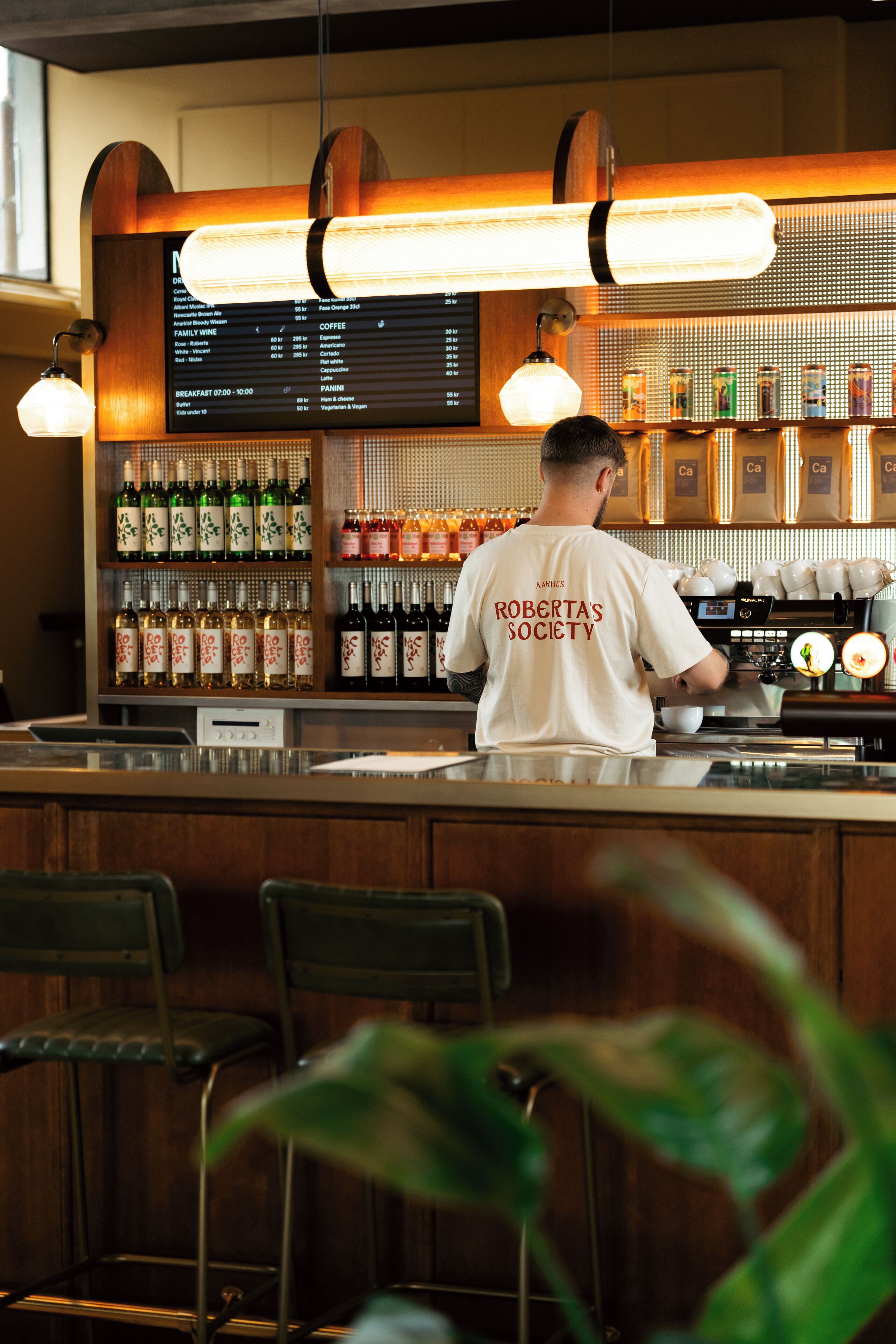 A bar with a menu board, shelves of liquor bottles, and a barista preparing drinks.