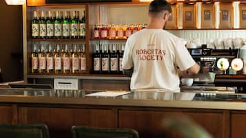 A bar with a menu board, shelves of liquor bottles, and a barista preparing drinks.