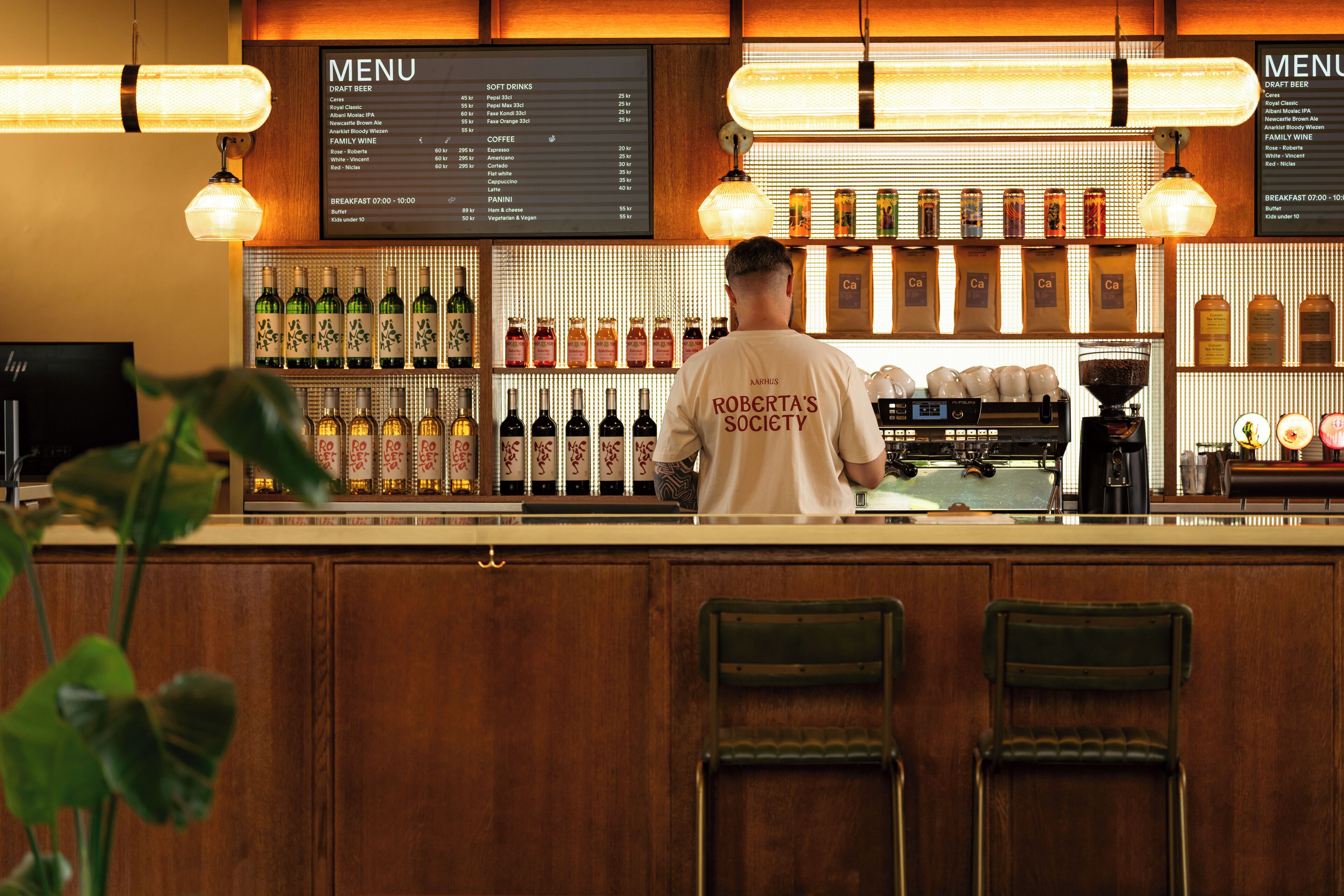 A bar area with a menu board, various bottles of alcohol, and a coffee machine.