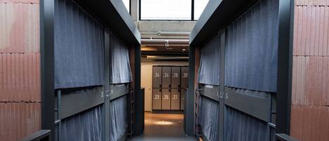 A corridor with lockers and a view of a room with a door.