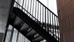 A staircase with metal railings and a view of a building's interior. - Robertas Society (Aarhus)