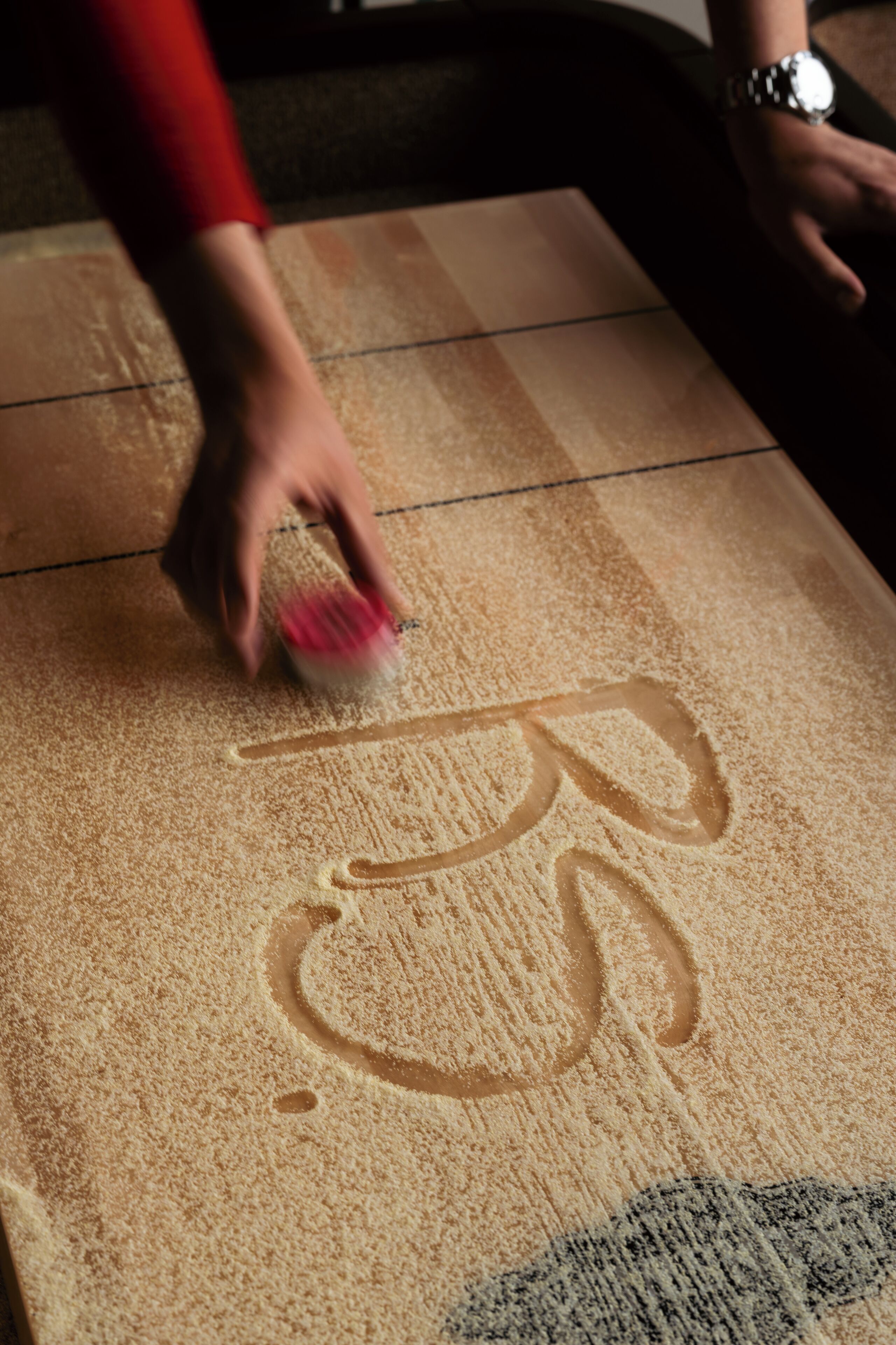 A hand smoothing a textured surface with a tool.