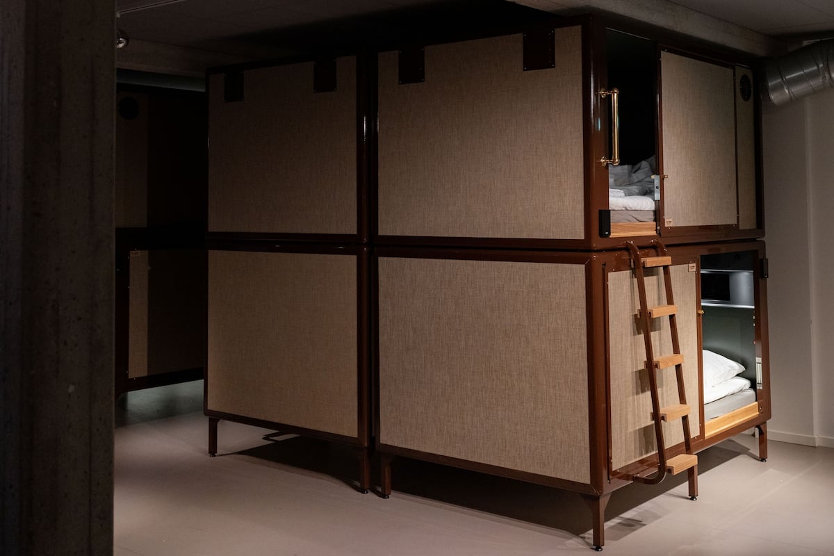 A bunk bed with a ladder, a wardrobe, and a small shelf unit.