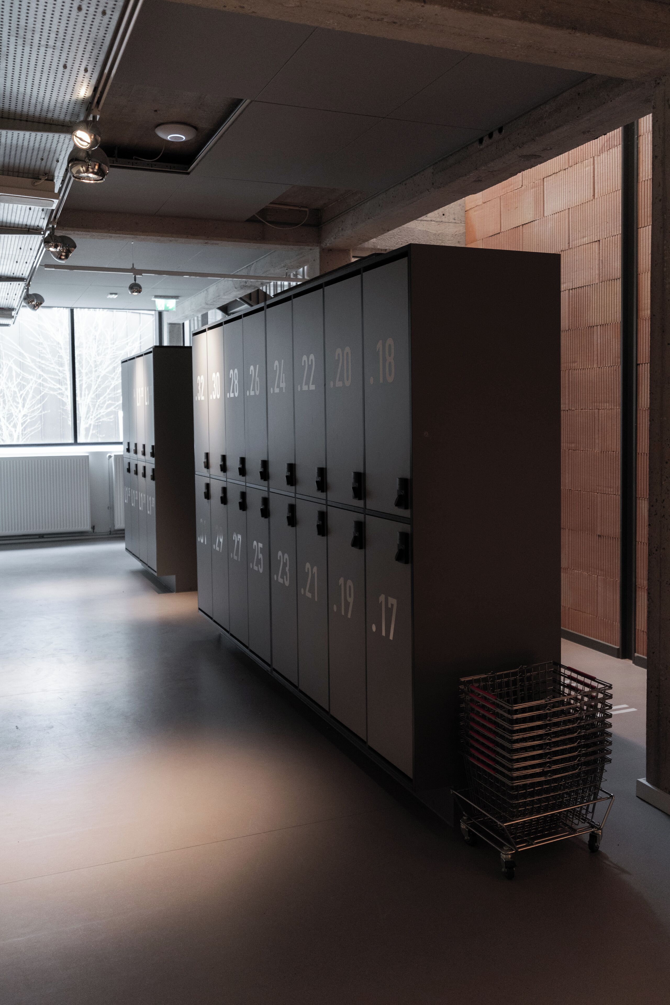 A locker room with numbered lockers and a metal cart.