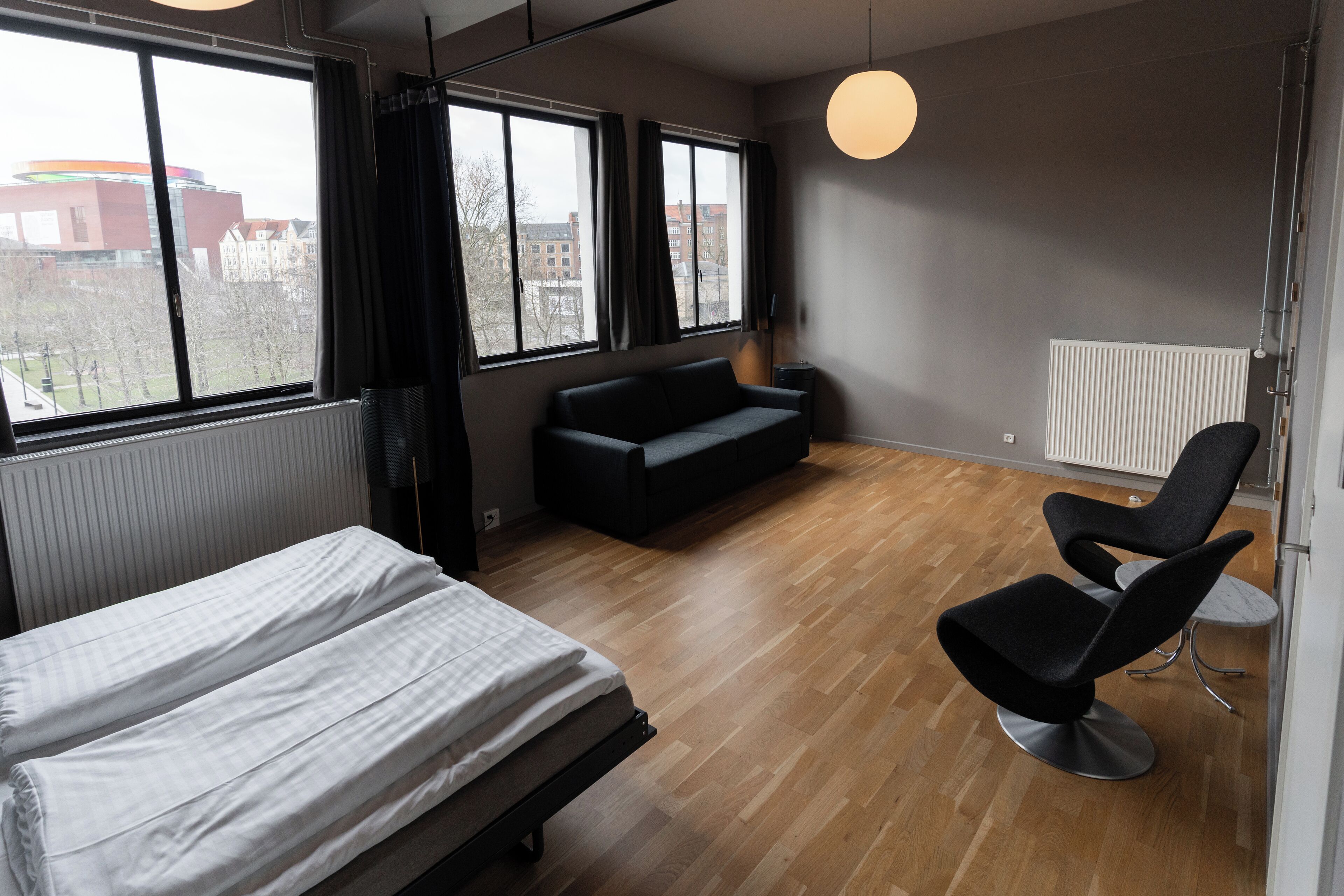 Moderni hotellihuone, jossa on sänky, sohva ja kaksi tuolia.