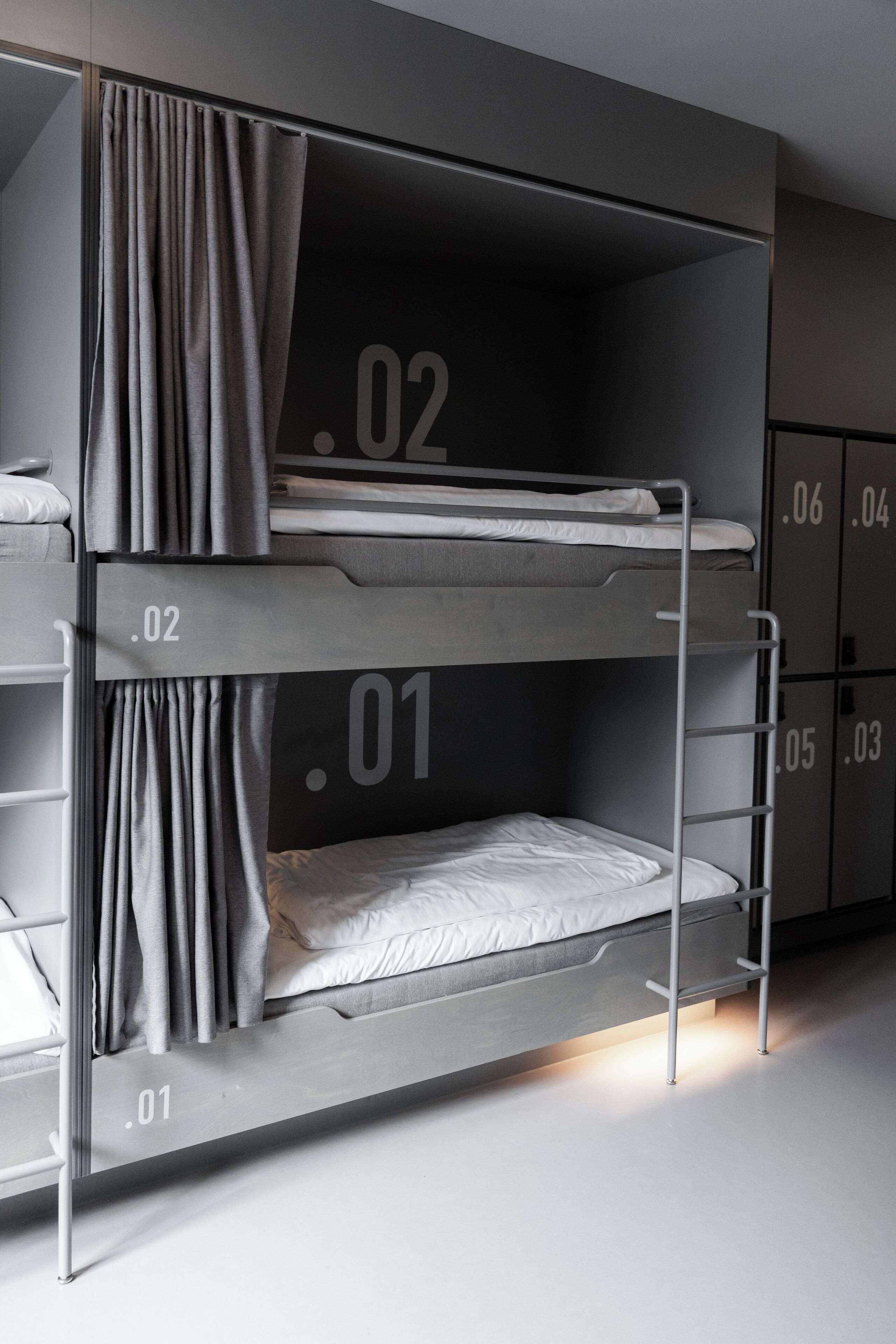 Een stapelbed met drie niveaus, elk voorzien van een nummer. Aan de linkerkant van het bovenste bed is een gordijn.