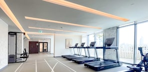 A modern gym with treadmills and rowing machines, large windows, and a clean, minimalist design. - LUX The Marina Vista Beachfront Suite 4 (Dubai)