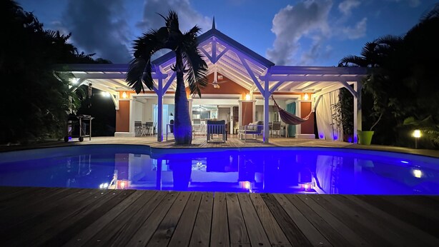 Une maison avec une piscine, un patio couvert et un hamac.