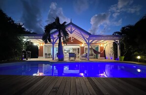 Een huis met een zwembad, een overdekt terras en een hangmat.