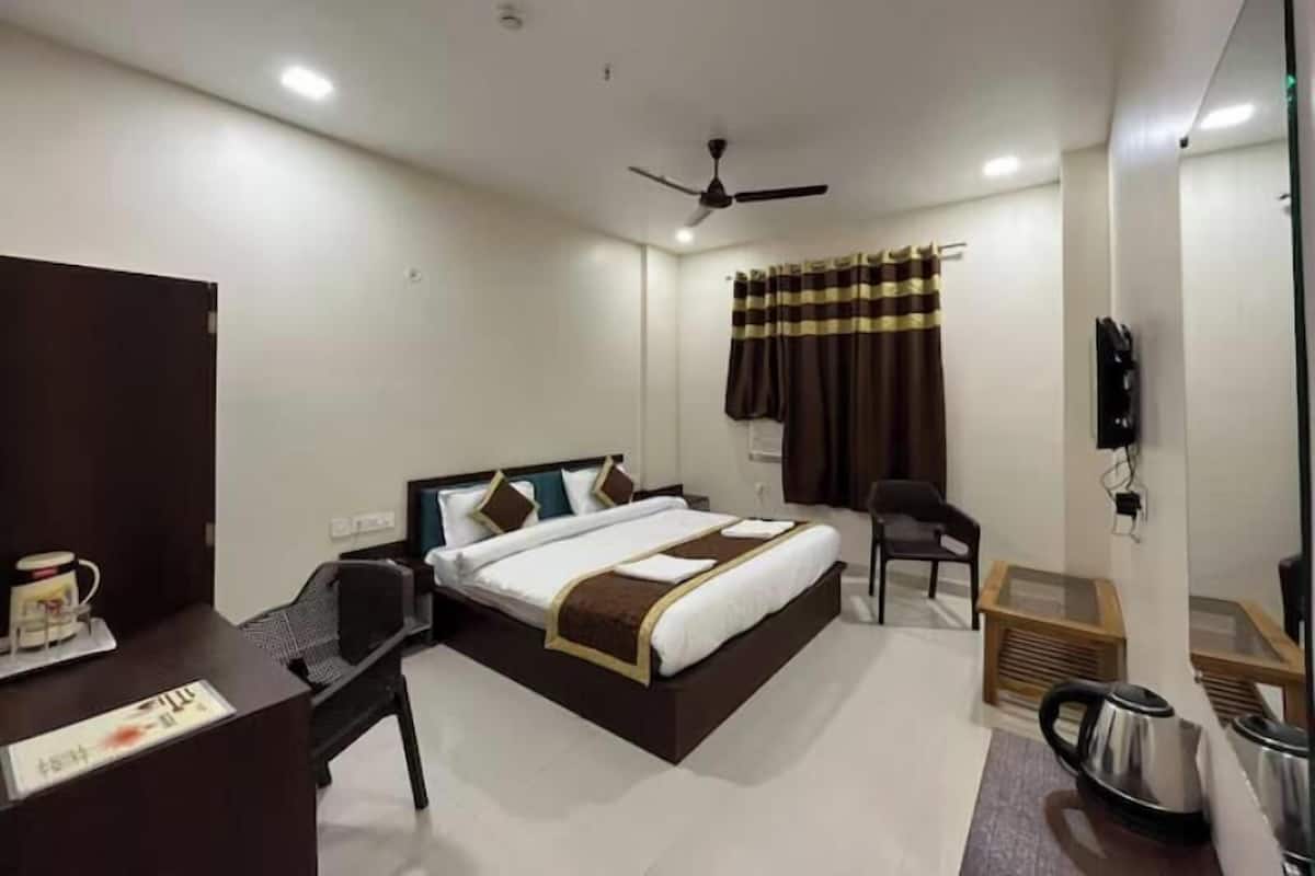 A hotel room with a bed, desk, chair, and a ceiling fan.