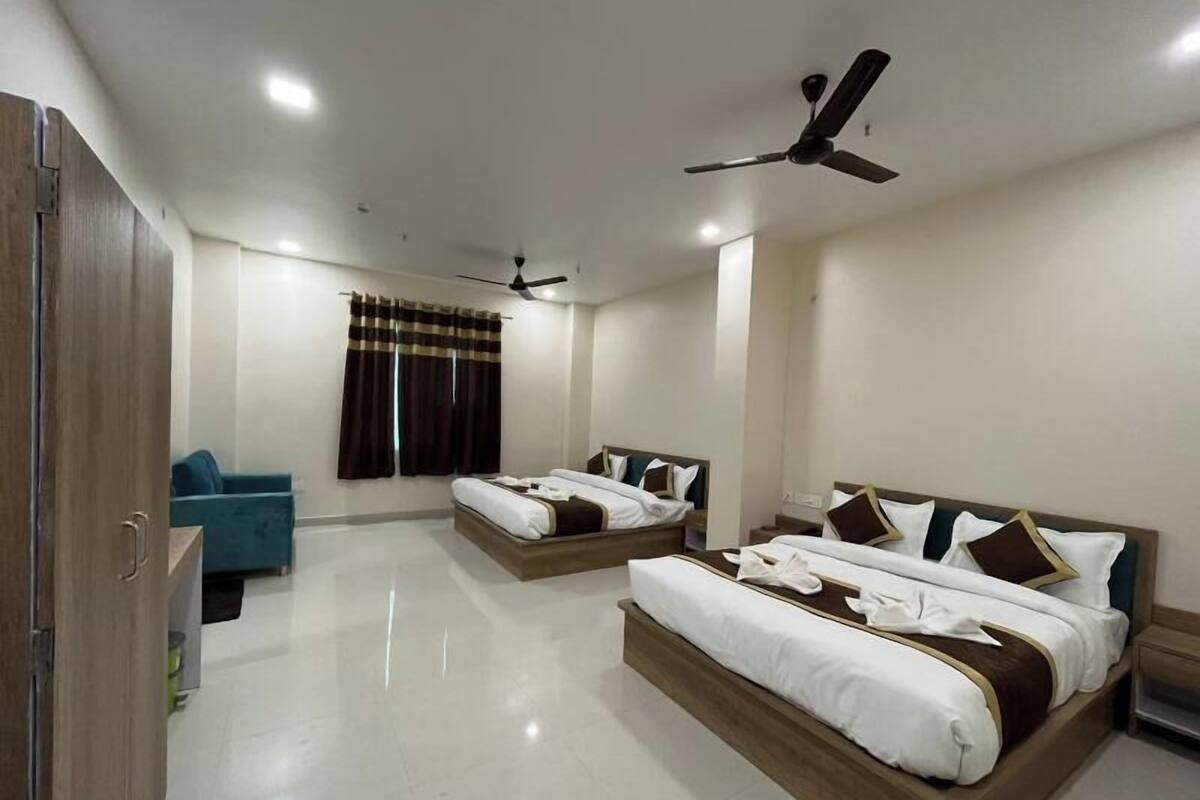 A hotel room with two beds, a wardrobe, a ceiling fan, and a window with curtains.