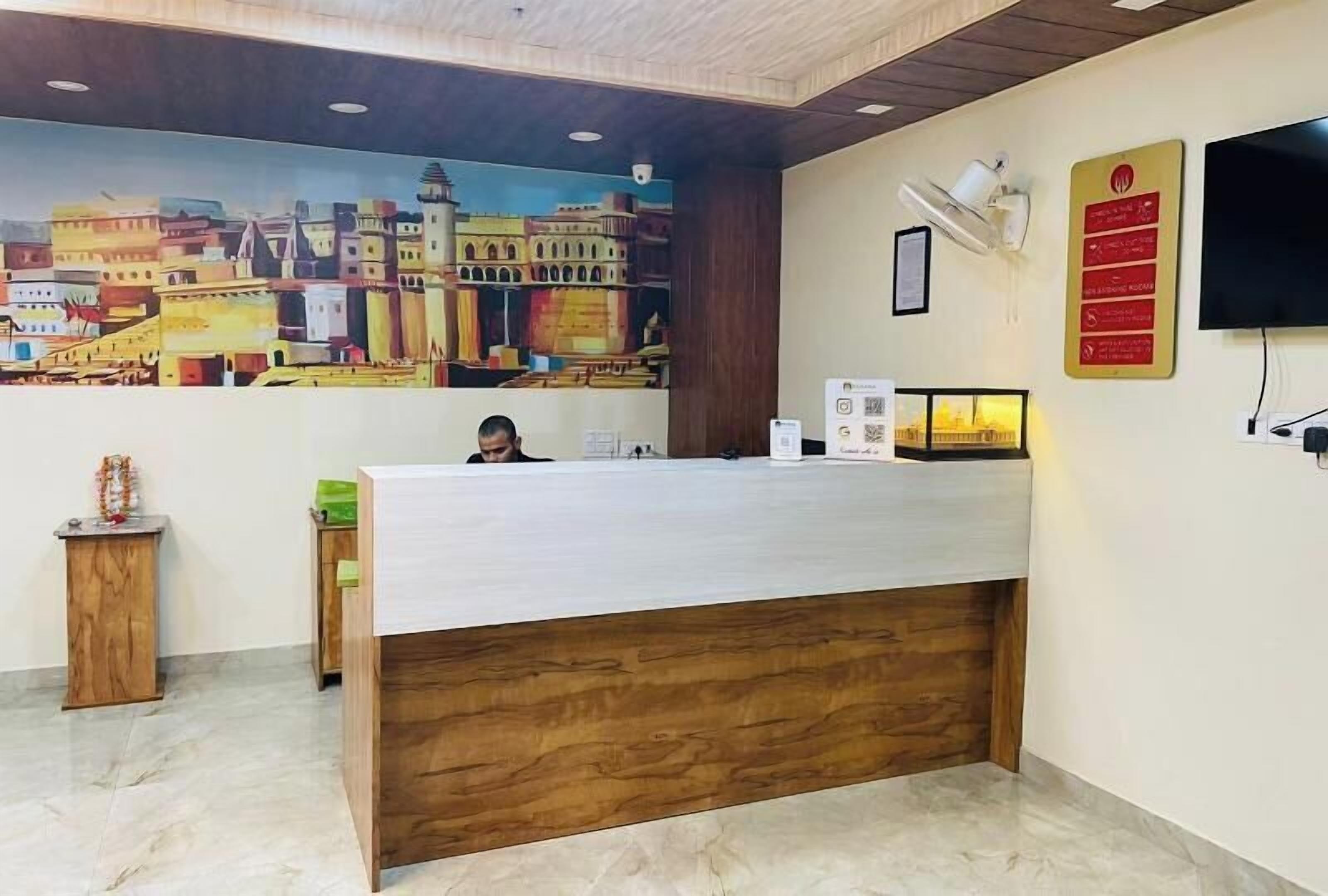 A reception desk with a cityscape mural, a flat-screen TV, and a fire safety sign.