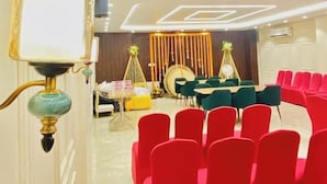 A modern hotel lobby with a seating area, a stage, and a decorative wall. - Hotel Kavana (Varanasi)