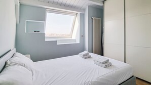 Una habitación de hotel moderna con una cama bien hecha, una ventana con vistas y un radiador.